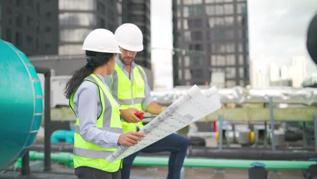Side view of two workers use plan or blueprint to  work in area of construction site.