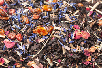 black tea with lemongrass, currant berries, sea buckthorn berries, rose petals, cornflower petals background top view