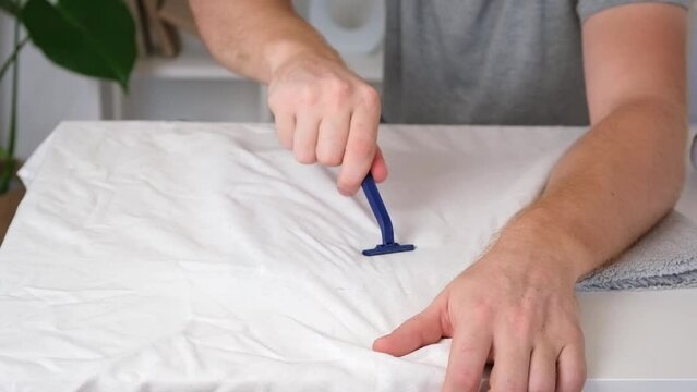 A man removes fabric pills using a disposable shaving machine. A razor for removing pellets.