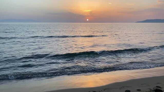Slow motion of waves crashing on golden beach at beautiful sunset. Sea waves splashing on the coastline. Summer vacation and beauty of nature concept