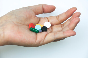 Female hand holding assorted pills isolated on white background. Copy space.