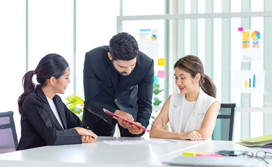 Two Asian young beautiful professional successful businesswoman employees presenting showing paperwork document on clipboard to Indian bearded male businessman manager to approve in meeting room