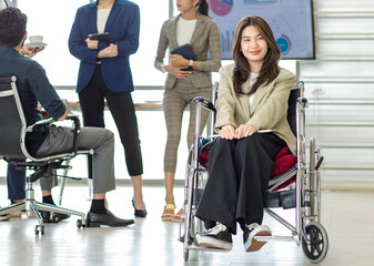 Group of millennial multinational multicultural Asian Indian businessmen and businesswomen with disabled handicapped partner sitting on wheelchair taking coffee break discussing together in office