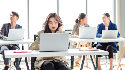 Fototapeta premium Closeup shot of millennial Asian young stressed depressed sleepy female businesswoman employee sitting holding hand on messy hair working on workstation desk via laptop notebook computer in office