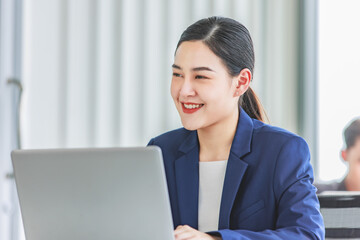 Closeup shot of millennial Asian young beautiful smart professional female businesswoman employee in formal suit sitting working on workstation desk typing laptop notebook computer in company office