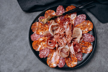 Salami on a black plate and olives and r white wine or Prosecco in a restaurant aperitif meal