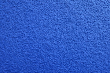 Fototapeta na wymiar Close view of wall with coarse vibrant blue roughcast finish