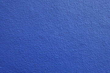 Surface of wall with coarse vibrant blue roughcast finish © Anna