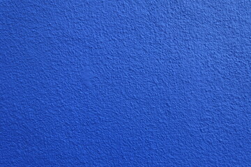 Texture of wall with coarse vibrant blue roughcast finish
