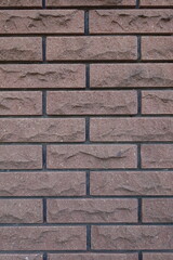 Surface of brown brick veneer wall with black mortar joints