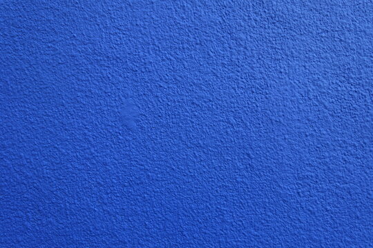 Texture of wall with coarse vibrant blue roughcast finish
