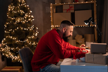 concept of starting a small and medium-sized business aspiring entrepreneur, in red suit, sits at table during break, flips through the news feed on a smartphone. good earnings during christmas sale