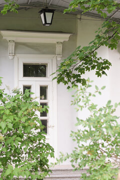 entrance door of an old stone manison in a country. vertical shot with green trees on a foreground, calm place in a country village, slow living concept. 