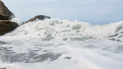 Close-up of sea wave with white foam with selective focus. Sea wave breaking on the shore. Rough sea of white foam and blur background and copy space