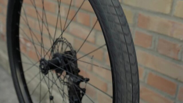 Black bicycle wheel spinning against red brick wall background. Bike service and care concept