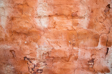 The texture of a red concrete wall with cracks and scratches can be used as a background