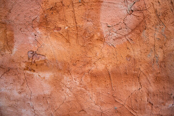 The texture of a red concrete wall with cracks and scratches can be used as a background