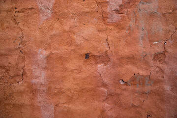The texture of a red concrete wall with cracks and scratches can be used as a background