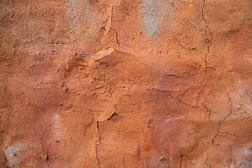 The texture of a red concrete wall with cracks and scratches can be used as a background