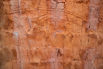 The texture of a red concrete wall with cracks and scratches can be used as a background