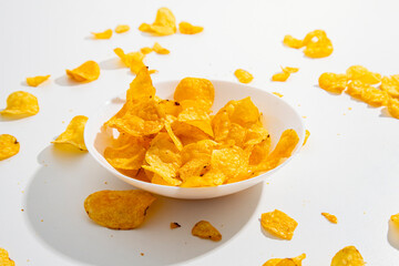 Golden chips in a white plate scattered on a white background