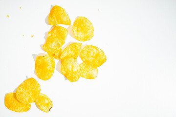 Fototapeta na wymiar Crispy golden potato chips are scattered on a white background. Top view, flat lay