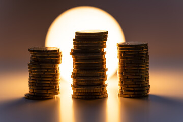 Coins stacked in front of a lit light bulb, representing the high cost of electricity.