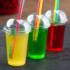 three multi-colored glasses with lemonade and straws