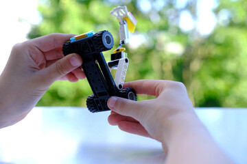 child's fingers move transformer car with manipulator, assembled from designer parts, green...