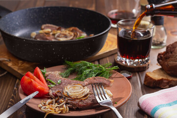 man pours dark craft beer from glass bottle into glass. focus on meat. healthy food concept.