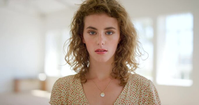 Portrait of a beautiful woman staring and blinking with a serious and unsmiling expression. Face of a worried young caucasian female contemplating while looking emotionless, stern and focused