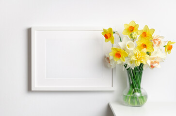Landscape frame mockup on white wall with daffodils flowers bouquet