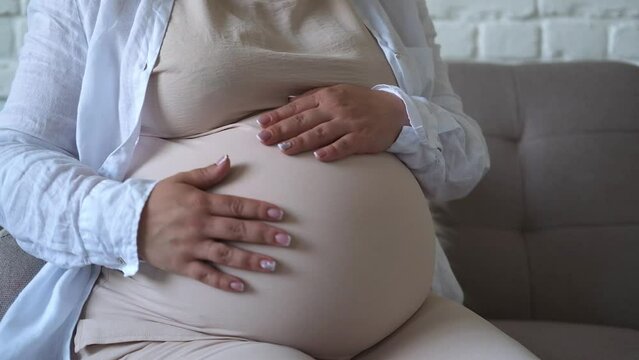 close up pregnant woman strokes her big belly. Maternity prenatal care