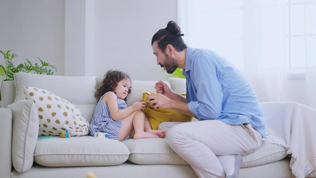 Happiness dad playing hug flying plane with girl daughter joy fun and exited in living room at home,father holding girl child flying around on sofa with love care tenderness and adorable moment
