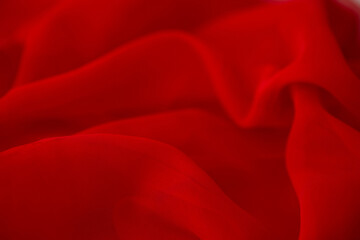 Red chiffon or silk material. Satin fabric close up background and texture with place for text. blurred background.