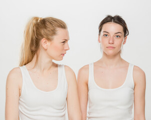 the girl tells the news to her friend. portrait of two girls in white t-shirts on a white background isolated.