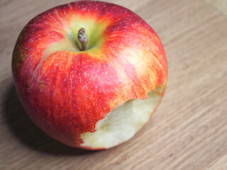 Big bitten apple on a wooden background. Ripe red apple. Close-up Gala apple.