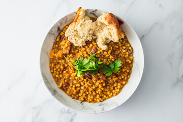 healthy plant-based food, vegan barley and lentil stew with homemade bread and freshly picked herbs from the garden