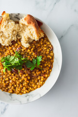 healthy plant-based food, vegan barley and lentil stew with homemade bread and freshly picked herbs from the garden