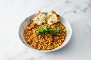healthy plant-based food, vegan barley and lentil stew with homemade bread and freshly picked herbs from the garden