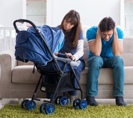 Young parents with their newborn baby in baby pram sitting on th