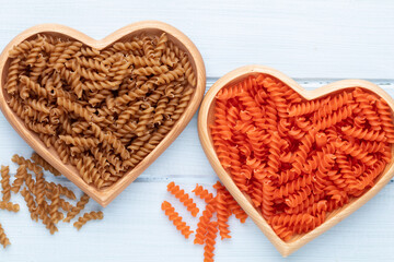 Red lentil fusilli pasta in a heart shaped wood bowl.