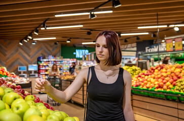 Woman in a supermarket at the shelf for fruits shopping green apple