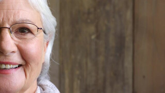 Closeup of smiling senior woman with optometry vision or optician prescription glasses. Half portrait, headshot and face of a happy, content woman with brown eyes against a wood copy space background
