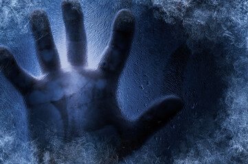 Human hand against frozen glass and blue background. Energy Crisis Concept