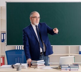 Aged male teacher in front of chalkboard