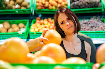 young woman in supermarket choosing grapefruits