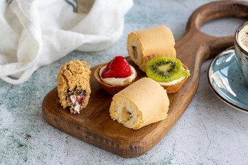 Delicious snacks. Roll cake, chocolate chip cake and fruit tart on a stone background. close up