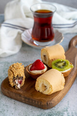 Delicious snacks. Roll cake, chocolate chip cake and fruit tart on a stone background. close up