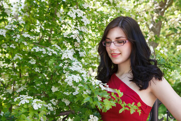 Fototapeta premium young brunette woman in a red dress walking in city park in summer